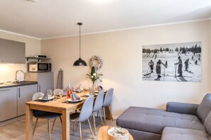 Una cocina moderna con microondas, una mesa de comedor para cuatro personas y un sofá gris en la sala.