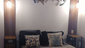 Ett sovrum med en säng, två sängbord, en vägglampa och en dekorativ väggdekoration.