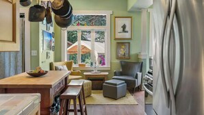 A kitchen with a central island, a dining area with chairs, a refrigerator, and a window with a view of the outdoors. - Capitol Hill House - Spacious, Cheery, Sun-filled (Seattle)