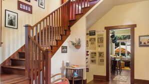 A wooden staircase leading to a second floor, a dining area with a table and chairs, and a hallway with framed pictures on the walls. - Capitol Hill House - Spacious, Cheery, Sun-filled (Seattle)