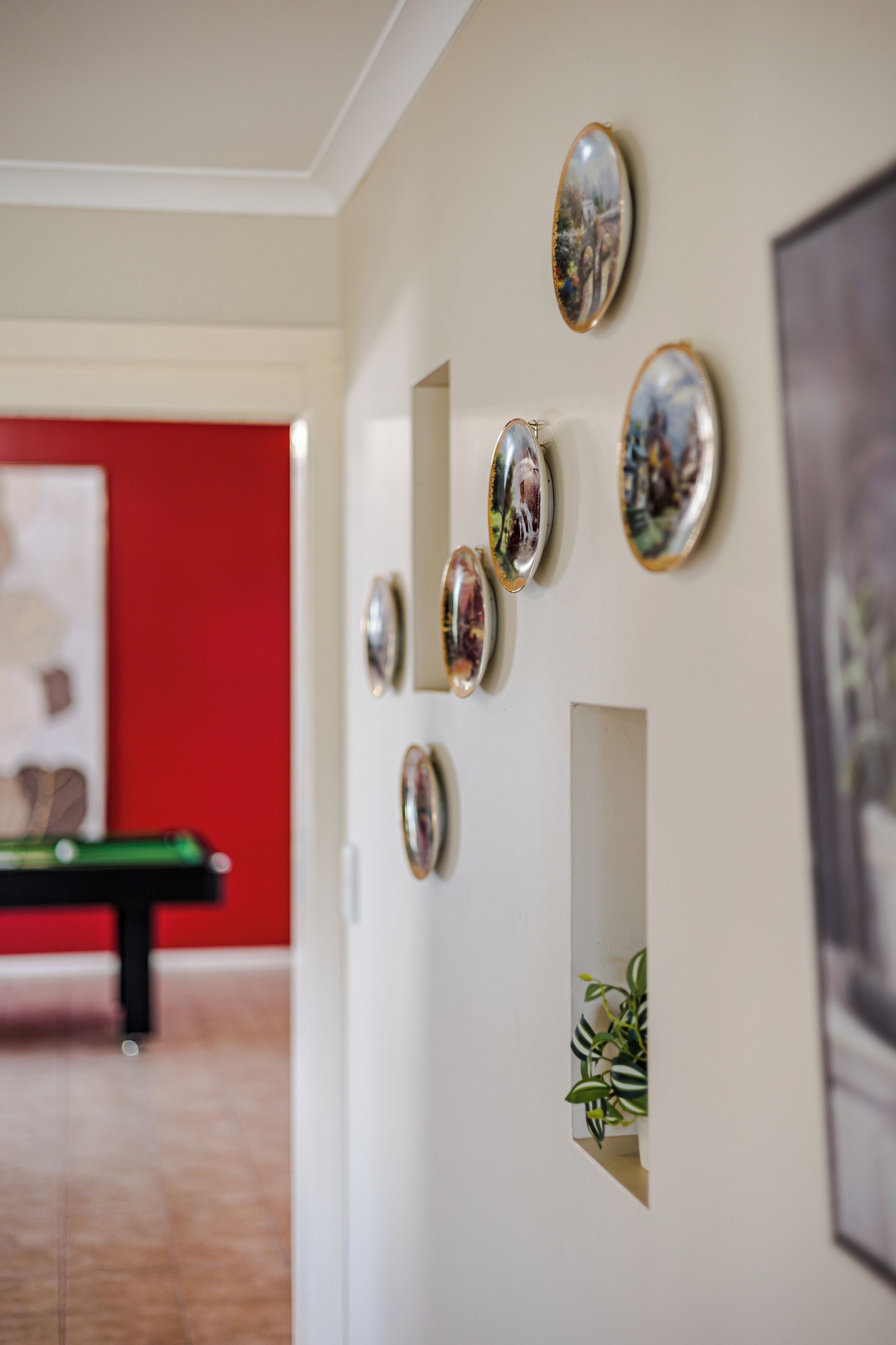 Une pièce avec une table de billard, un mur orné de miroirs ovales et un tableau encadré.