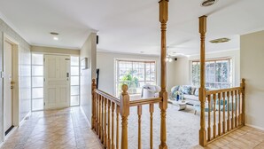 Un vaste espace de vie agrémenté d’un escalier en bois, de grandes fenêtres et d’un coin salon confortable.