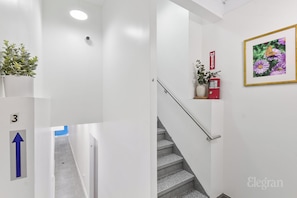 A modern interior with a staircase, a fire extinguisher, and a framed floral artwork.