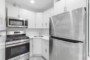 A modern kitchen with stainless steel appliances, a microwave, oven, and a refrigerator.