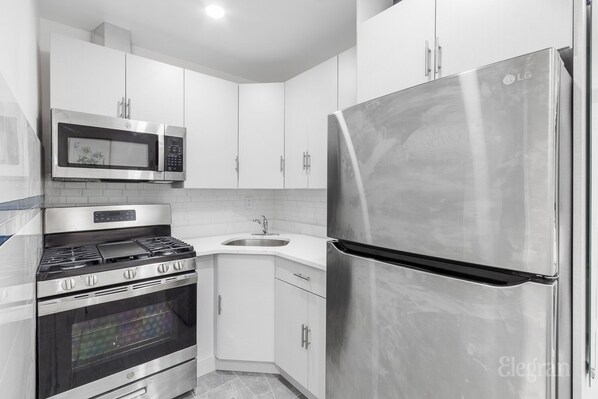 A modern kitchen with stainless steel appliances, a microwave, oven, and a refrigerator.