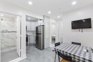 A compact kitchen with a refrigerator, a sink, and a dining area with a checkered tablecloth.