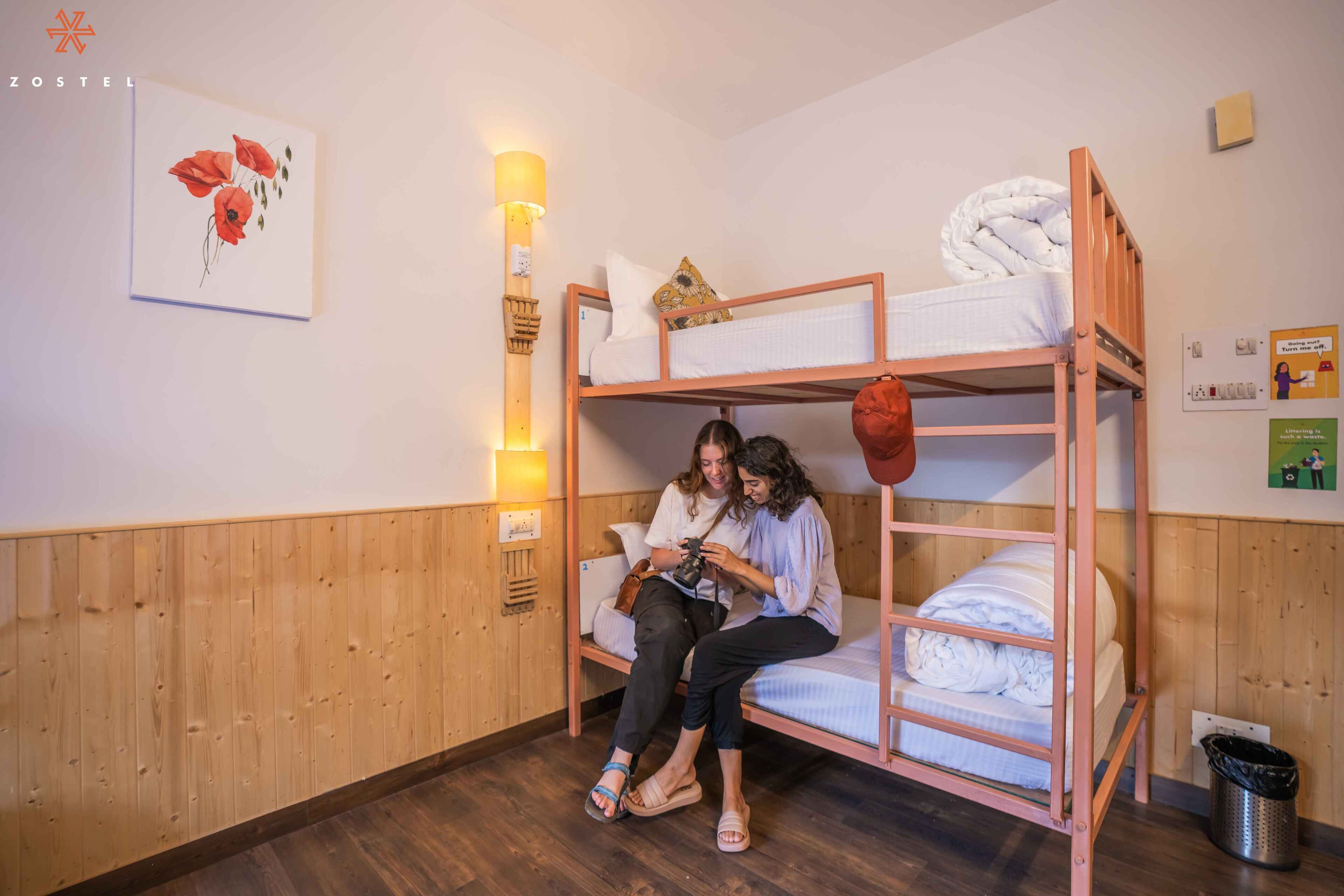 A bunk bed room with wooden paneling, a wall-mounted lamp, and a framed artwork.