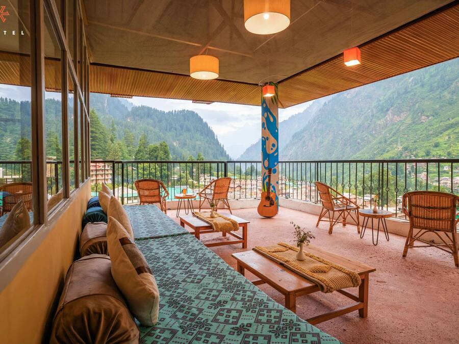 A balcony with wicker furniture, a guitar, and a view of mountains.