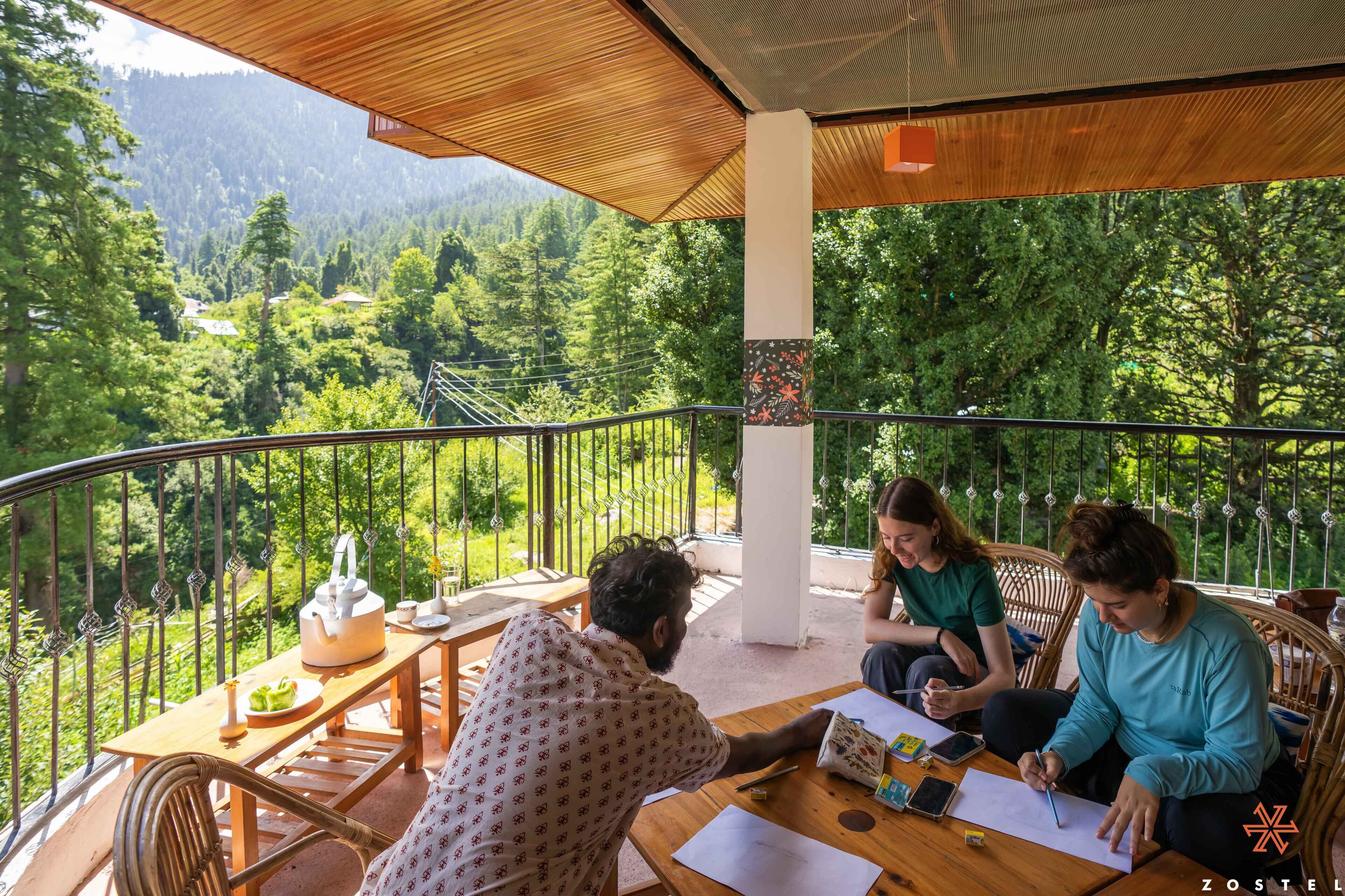 Un balcón con mesa y sillas de madera, y vista a un paisaje boscoso.