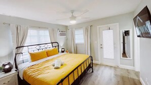 A bedroom with a bed, curtains, a ceiling fan, and a TV on the wall. - Spacious 1-Bedroom in Coral Ridge with King Bed, Sofa Bed & Pool Access (fort lauderdale)