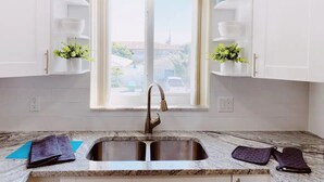 Una cocina con armarios blancos, un lavamanos doble y una ventana con vistas al exterior.