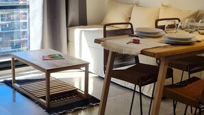 Una sala de estar moderna con comedor, un ventanal con cortinas, un cuadro en la pared y un equipo de aire acondicionado.