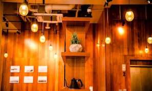 A wooden interior with a shelf holding a cactus, a kettle, and a wall-mounted projector.