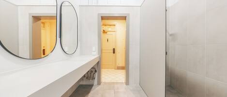 Une salle de bain moderne avec deux miroirs, un lavabo blanc et un sol carrelé.