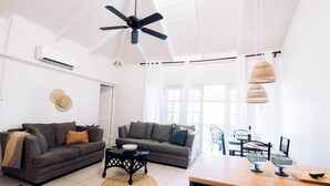 Un vaste espace de vie comprenant deux canapés, une table à manger et un ventilateur de plafond.