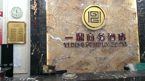 A reception desk with a marble wall and a clock. - Yiding Business Hotel (Yuxi Building Expo Center Subway Station Branch) (Zhengzhou)