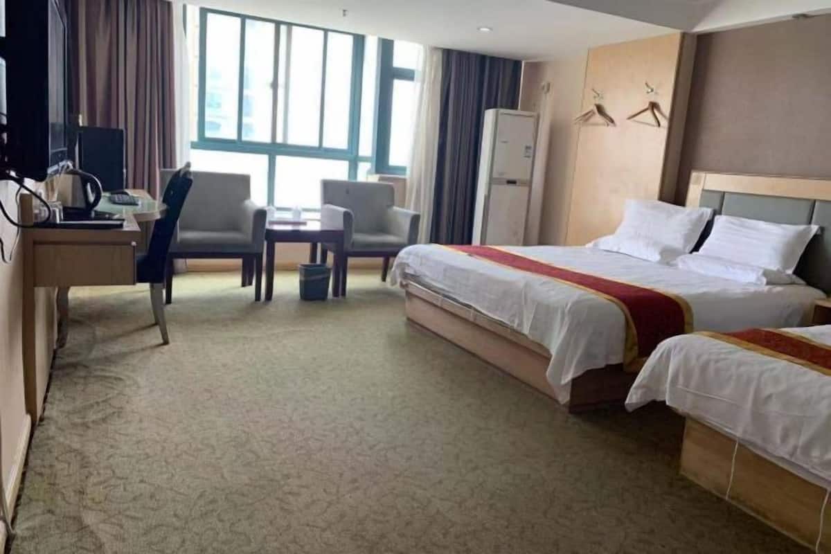 A hotel room with a bed, a desk, a chair, a television, and a wardrobe.