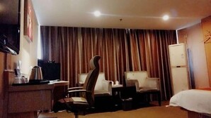 A hotel room with a bed, a desk, a chair, a television, and a curtain. - Yiding Business Hotel (Yuxi Building Expo Center Subway Station Branch) (Zhengzhou)