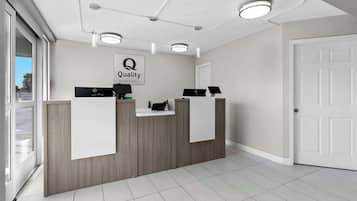 Un área de recepción con un mostrador de madera, un cartel que dice "Quality by Choice Hotels" y una puerta a la derecha.