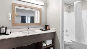 Un baño moderno con un espejo grande, un lavamanos, un inodoro y una ducha.