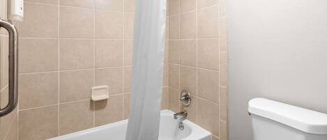 A bathroom with a bathtub, a showerhead, and a toilet.