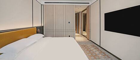 A hotel room with a large bed, a flat-screen TV mounted on the wall, and a carpeted floor.