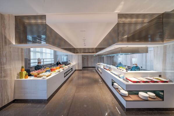 Una moderna presentación de buffet con mostradores de mármol y una barra larga.