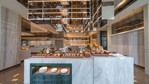 A modern hotel lobby with a central breakfast bar, marble flooring, and a high ceiling with exposed beams and lighting fixtures. - YTL ChangChengYunYue Hotel (Wenzhou)