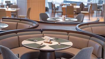 A modern restaurant with round tables and cushioned seating.