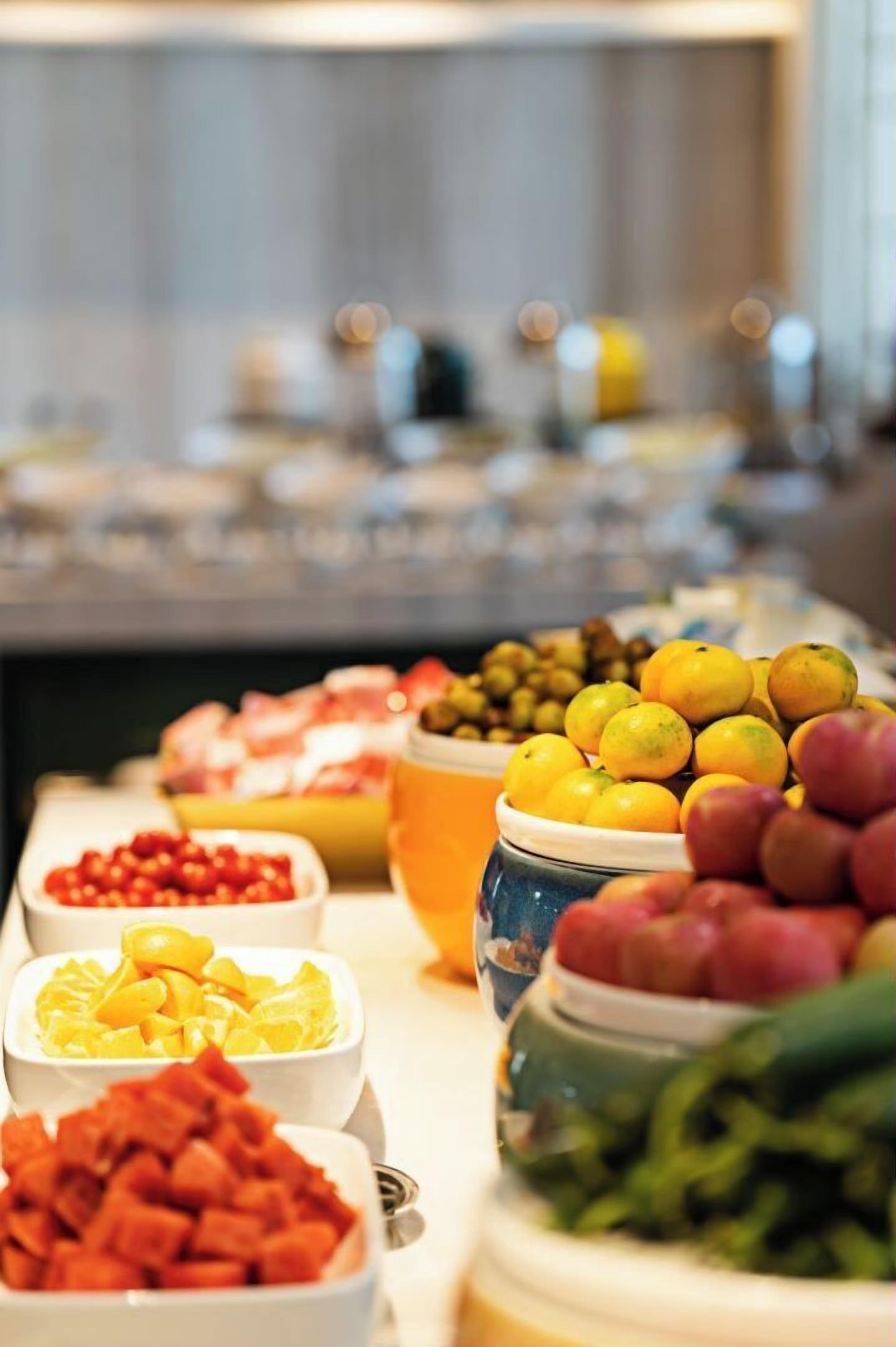 En buffet med et udvalg af mad, herunder frugt, grøntsager og kød.