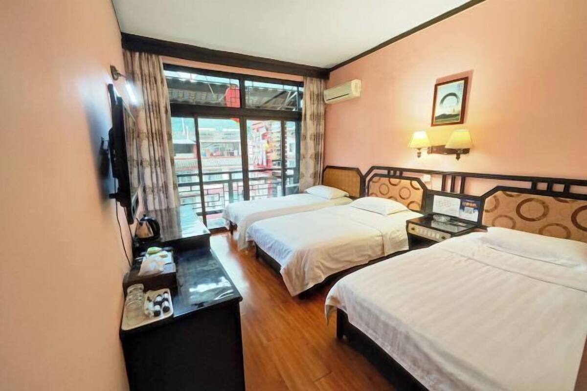 A hotel room with two beds, a desk, a TV, and a window with curtains.