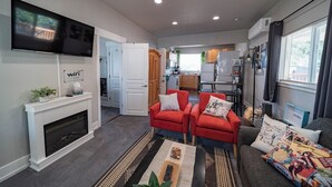 Ein modernes Wohnzimmer mit Kamin, Flachbildfernseher und einer Küche im Hintergrund.