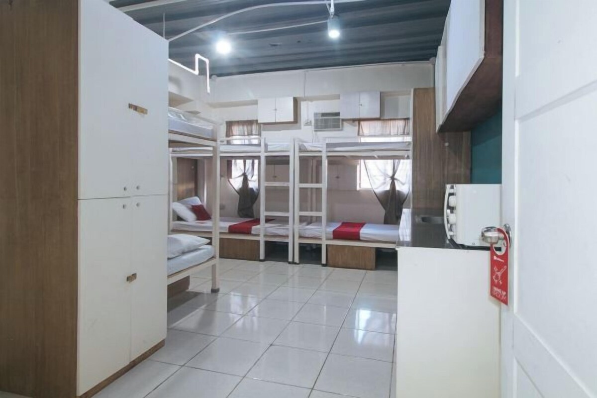 A room with bunk beds, a wardrobe, and a kitchenette.