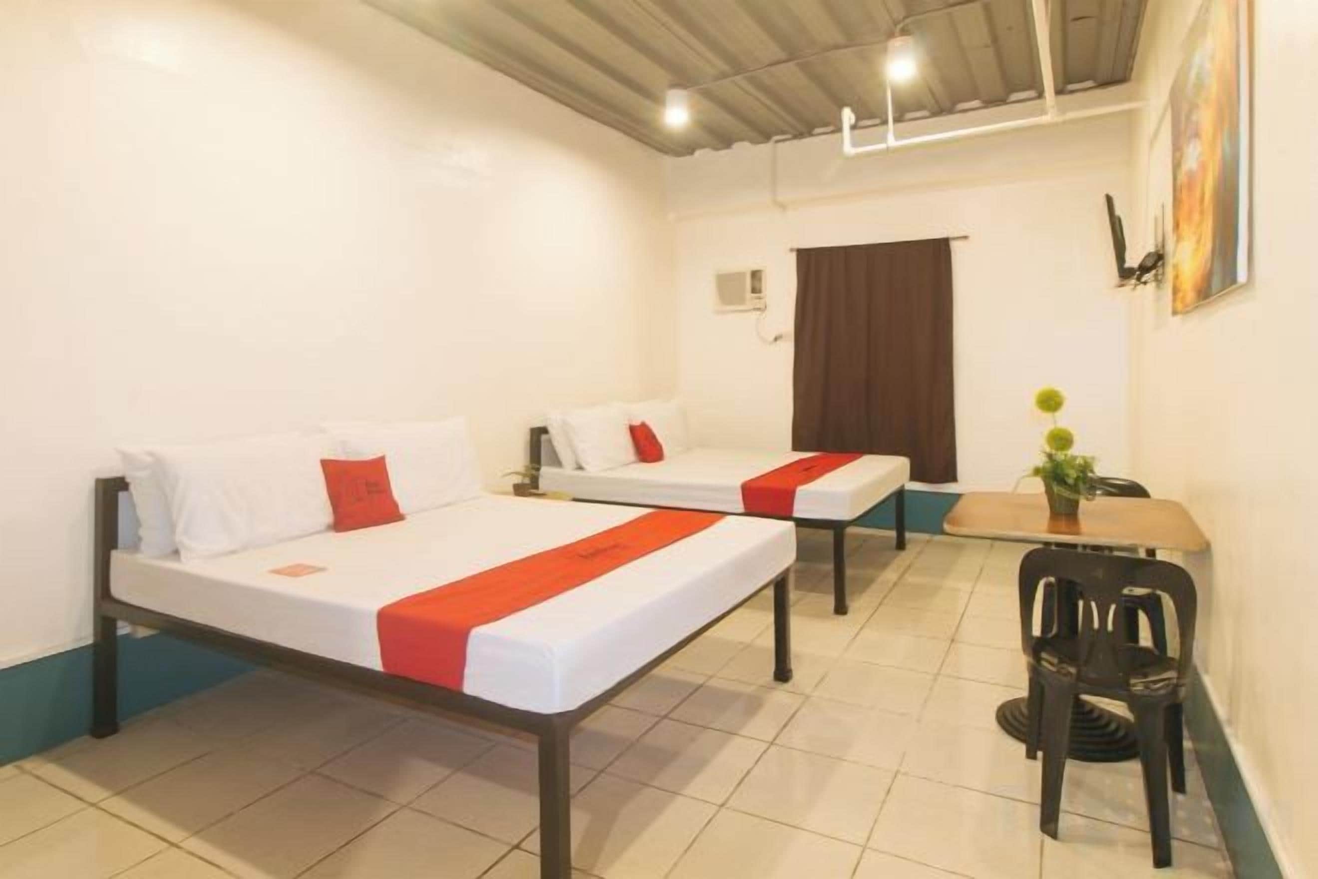 A hotel room with two beds, a dining table, and a chair.
