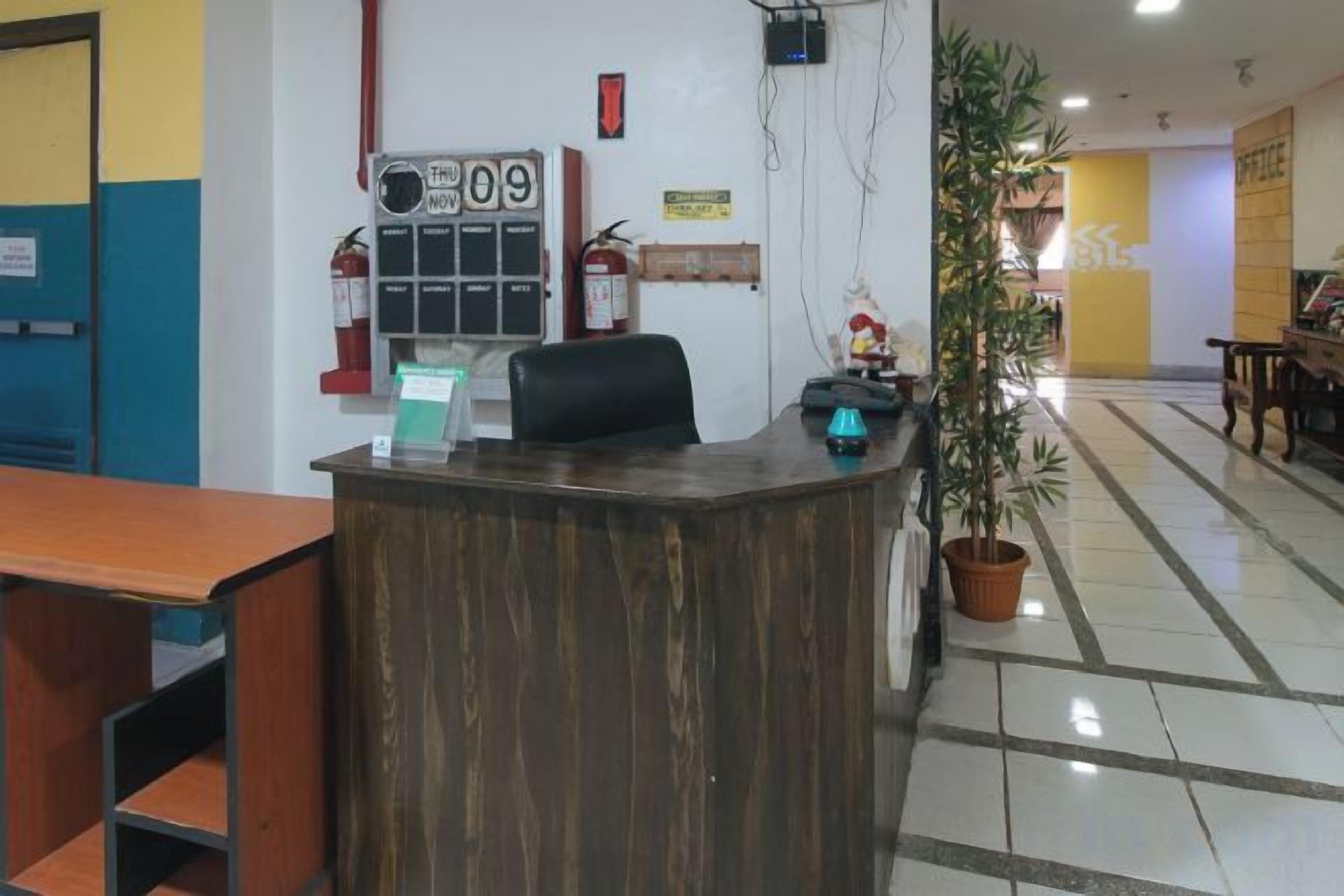 A reception desk with a telephone, a fire alarm, and a potted plant.