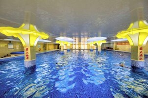 Una piscina interior con varias pistas, iluminación amarilla en el techo y pilares con texto rojo.