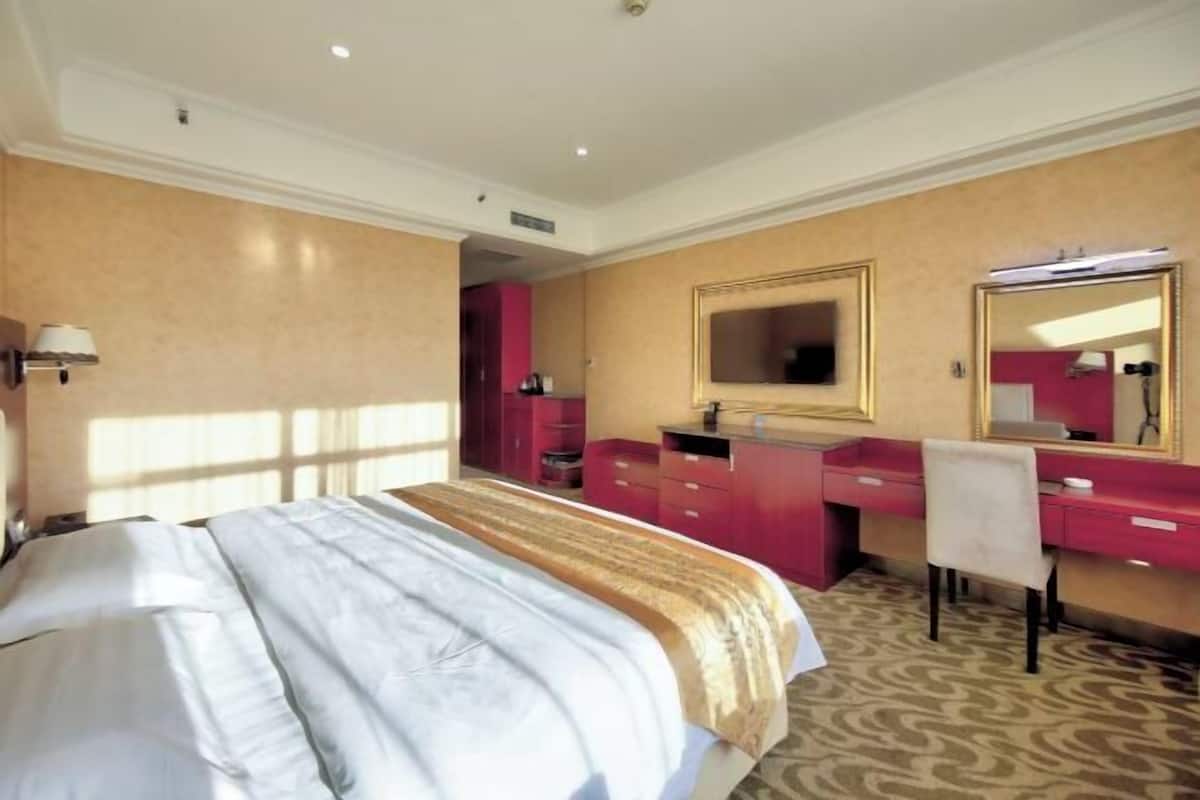 Habitación de hotel con una cama grande, un tocador con espejo y un escritorio.