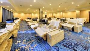 Une chambre d’hôtel avec plusieurs lits disposés en rangées, une grande surface recouverte de moquette et un comptoir d’accueil.