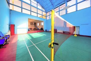 An indoor sports hall with a volleyball net, seating area, and a staircase leading to an upper level. - Jinyou Hotel (Liuhe)