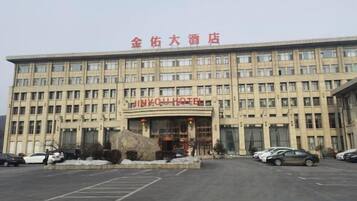 A multi-story hotel building with a large entrance and a parking lot in front.