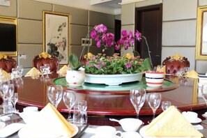 A dining table set with multiple plates, glasses, and a centerpiece with flowers. - Jinyou Hotel (Liuhe)
