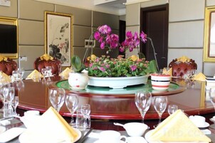 Una mesa de comedor dispuesta con varios platos, vasos y un centro de mesa con flores.