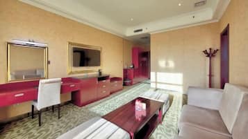 Una habitación de hotel con cama, escritorio con silla, sofá, espejo y armario.