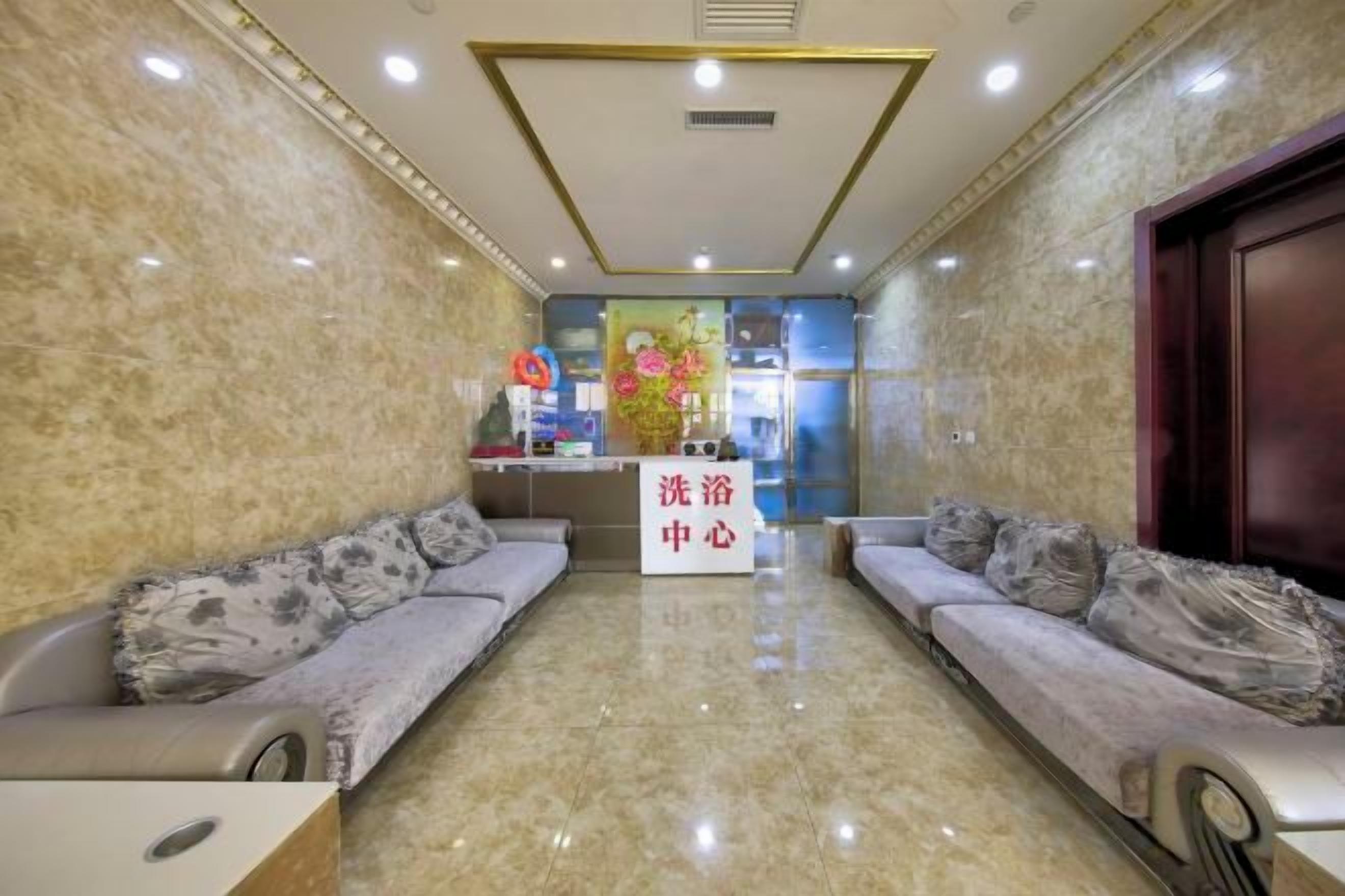 A hotel lobby with marble walls, a reception desk, and two sofas with cushions.