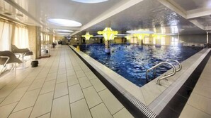 Une piscine dotée d’un sol carrelé et d’un plafond agrémenté de puits de lumière circulaires.