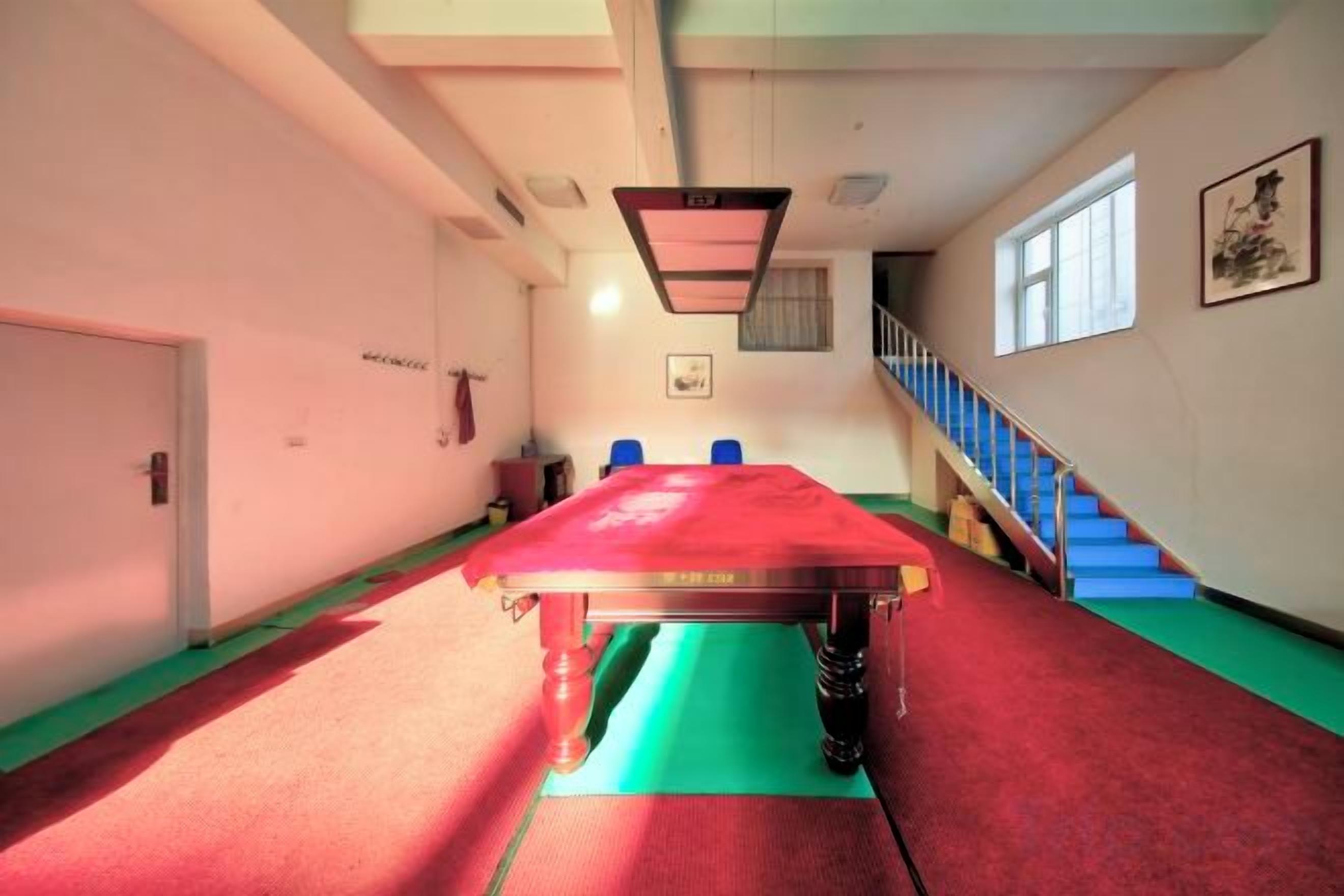 Una habitación con una larga mesa roja, una escalera y una puerta.