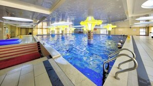 Une piscine intérieure dotée de plusieurs couloirs, un vestiaire avec un tapis rouge et un éclairage moderne.