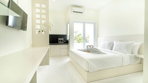 Een moderne hotelkamer met een groot bed, een aan de muur bevestigde televisie, een kitchenette en een groot raam met uitzicht op de omgeving.
