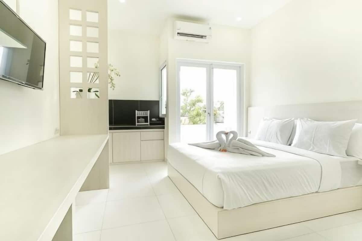 Una habitación de hotel moderna con una cama, televisión, kitchenette y un amplio ventanal.