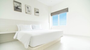 A minimalist bedroom with a large bed, a window with a view, and three framed pictures on the wall. - The Axara Bali (Jimbaran)
